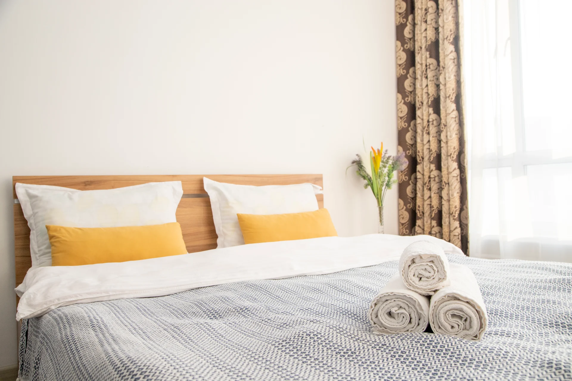 Chambre soignée avec linge de lit crème et coussins orange, préparée pour l'arrivée d'un voyageur Airbnb